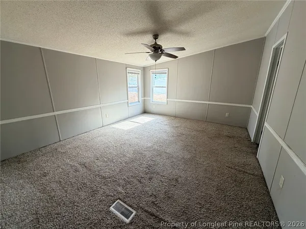 en empty room with windows and ceiling fan