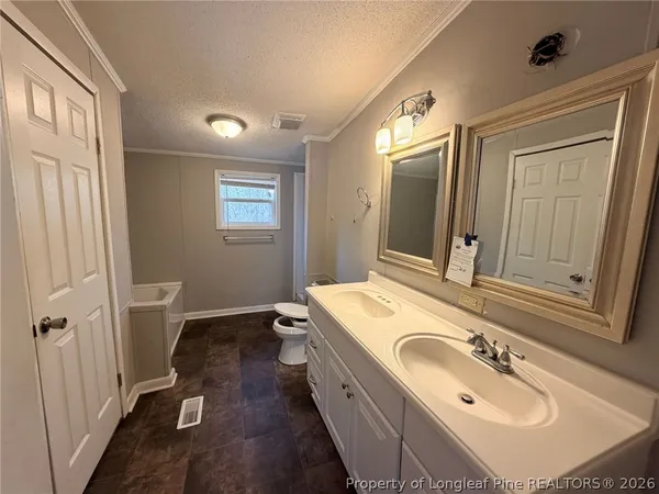 a spacious bathroom with a double vanity sink a mirror and a toilet