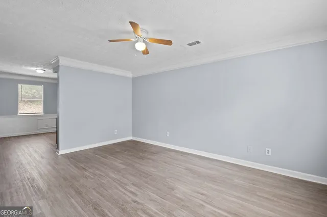 an empty room with wooden floor and windows