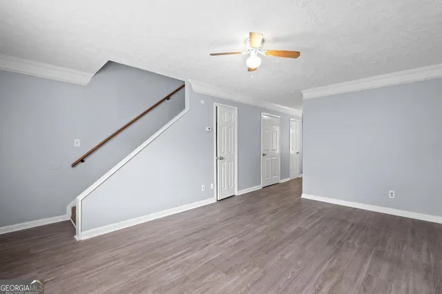 a view of an empty room with wooden floor and chandelier