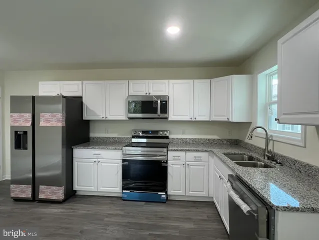 a large kitchen with cabinets wooden floor and stainless steel appliances