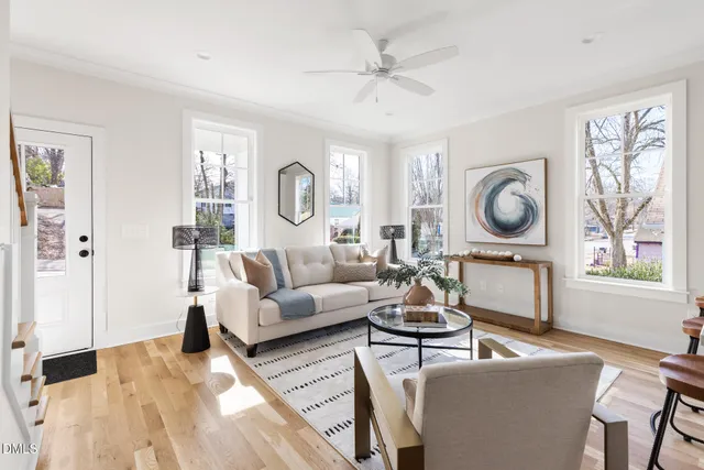 a living room with furniture a clock on wall and a window