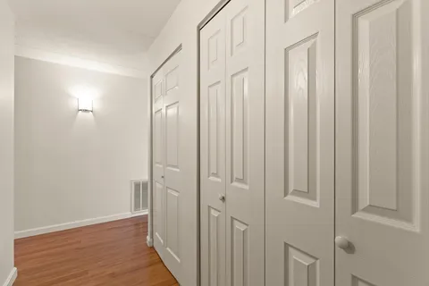 a view of a white house with a yard plants and large tree