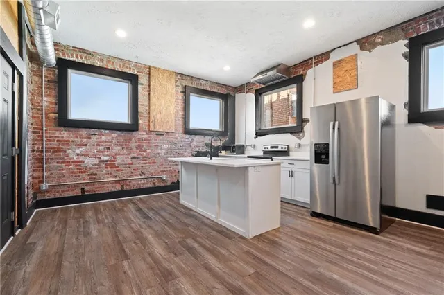a view of an empty room with wooden floor and a large window
