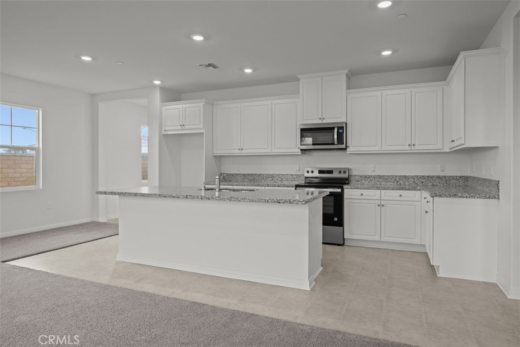 25632 Ranch House Road Homeland, CA 92548 - Photo 17 of 26 a kitchen with kitchen island granite countertop white cabinets and stainless steel appliances