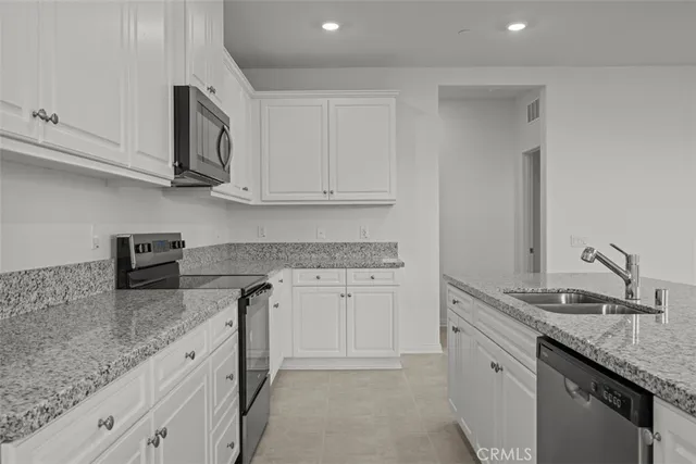 a kitchen with stainless steel appliances granite countertop white cabinets and a stove a oven with white countertops