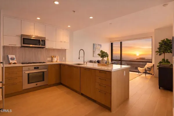 a kitchen with stainless steel appliances granite countertop a stove top oven a sink dishwasher a dining table and chairs with wooden floor