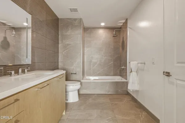 a bathroom with a bathtub shower sink vanity and toilet