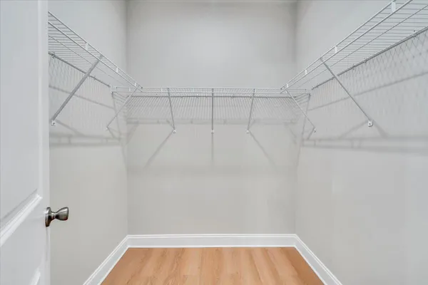a view of an empty room with wooden floor and windows