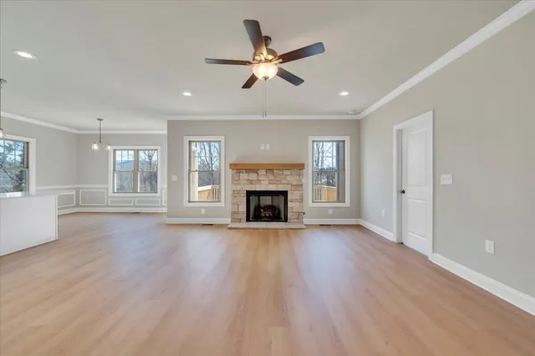a view of an empty room with wooden floor fireplace and a window