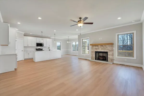 a view of a big room with wooden floor a kitchen view and a fireplace