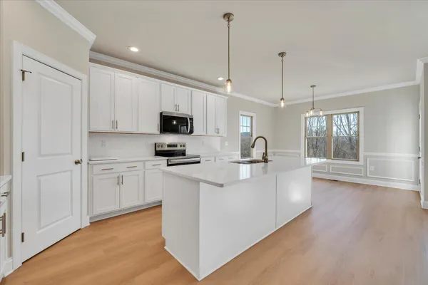 a kitchen with stainless steel appliances granite countertop a refrigerator a sink dishwasher a oven with white cabinets and wooden floor