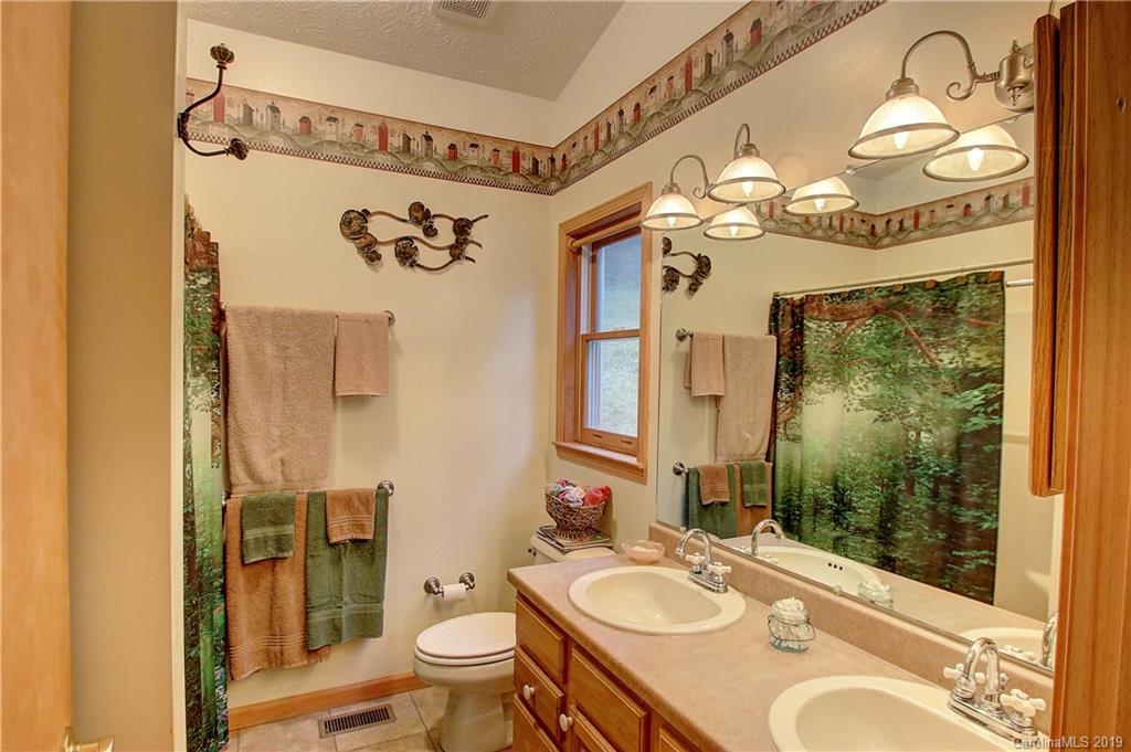 951 Price Town Road Clyde, NC 28721 - Photo 11 of 36 a bathroom with a granite countertop sink mirror vanity and toilet