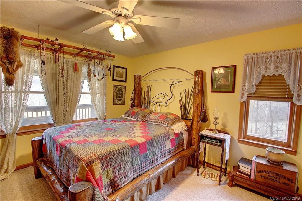 951 Price Town Road Clyde, NC 28721 - Photo 12 of 36 a bedroom with a bed next to a window and a chandelier