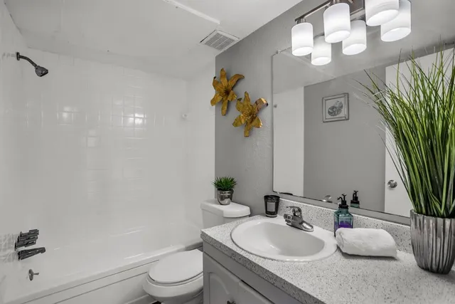 a bathroom with a granite countertop sink a toilet and a mirror