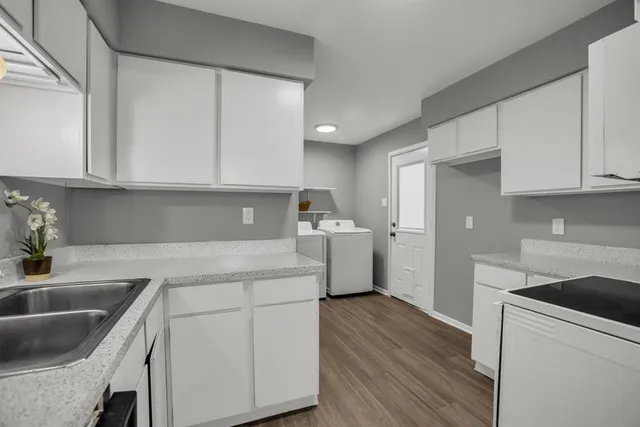 a kitchen with a sink dishwasher a stove top oven a refrigerator and cabinets