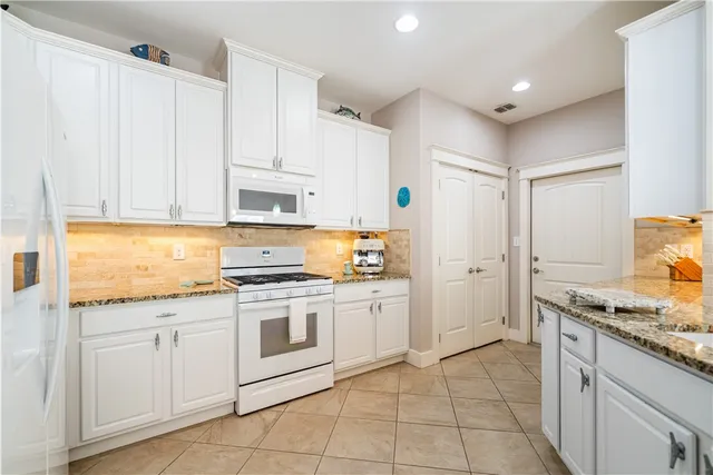 a kitchen with granite countertop white cabinets and white appliances