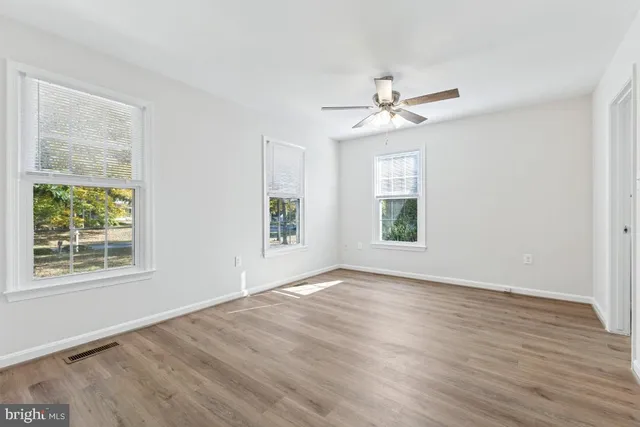 a view of an empty room with a window and wooden floor