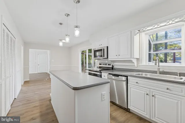 a kitchen with white cabinets appliances and a window