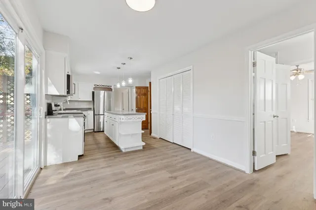 a view of kitchen with refrigerator and white cabinets