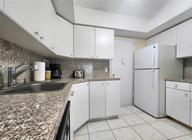 a kitchen with granite countertop a refrigerator and a sink