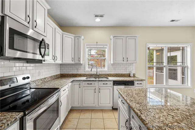 a kitchen with stainless steel appliances granite countertop a sink stove and cabinets