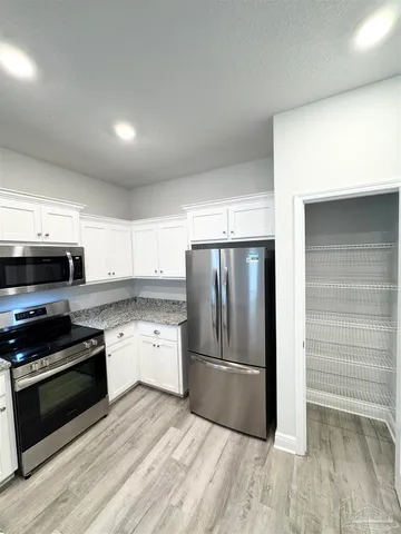 a kitchen with granite countertop a refrigerator stove and oven