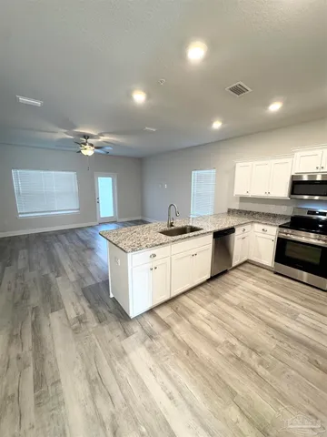 a large kitchen with granite countertop a sink and cabinets