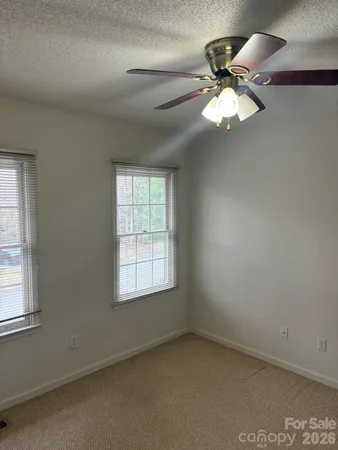 an empty room with windows and fan