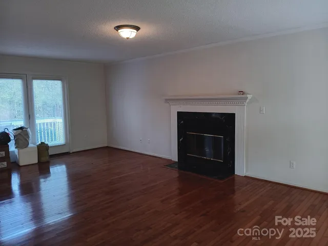 an empty room with wooden floor fireplace and windows