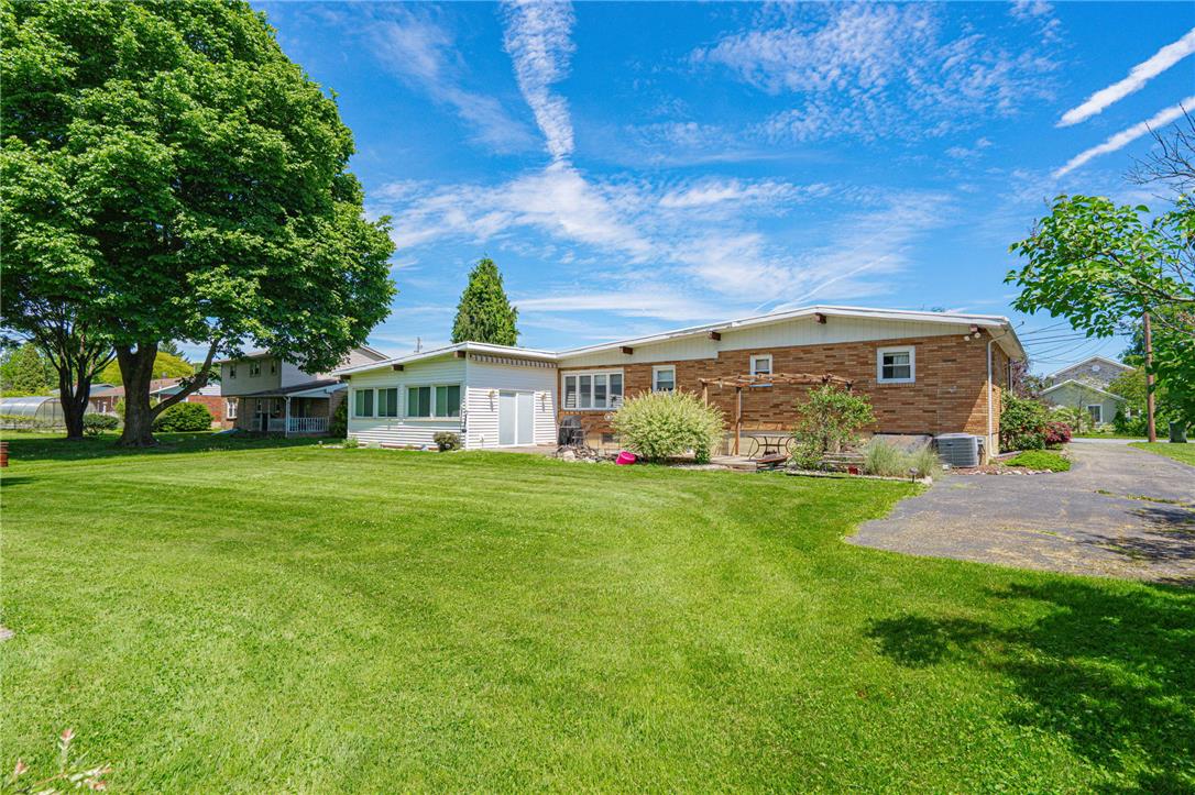 579 Cherry Road Northampton, PA 18067 - Photo 51 of 57 A spacious backyard with mature trees, verdant lawn, and a brick-sided home with an inviting sunroom.
