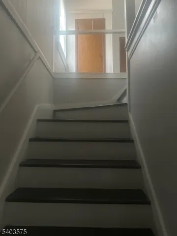 a view of a hallway with wooden floor and a window