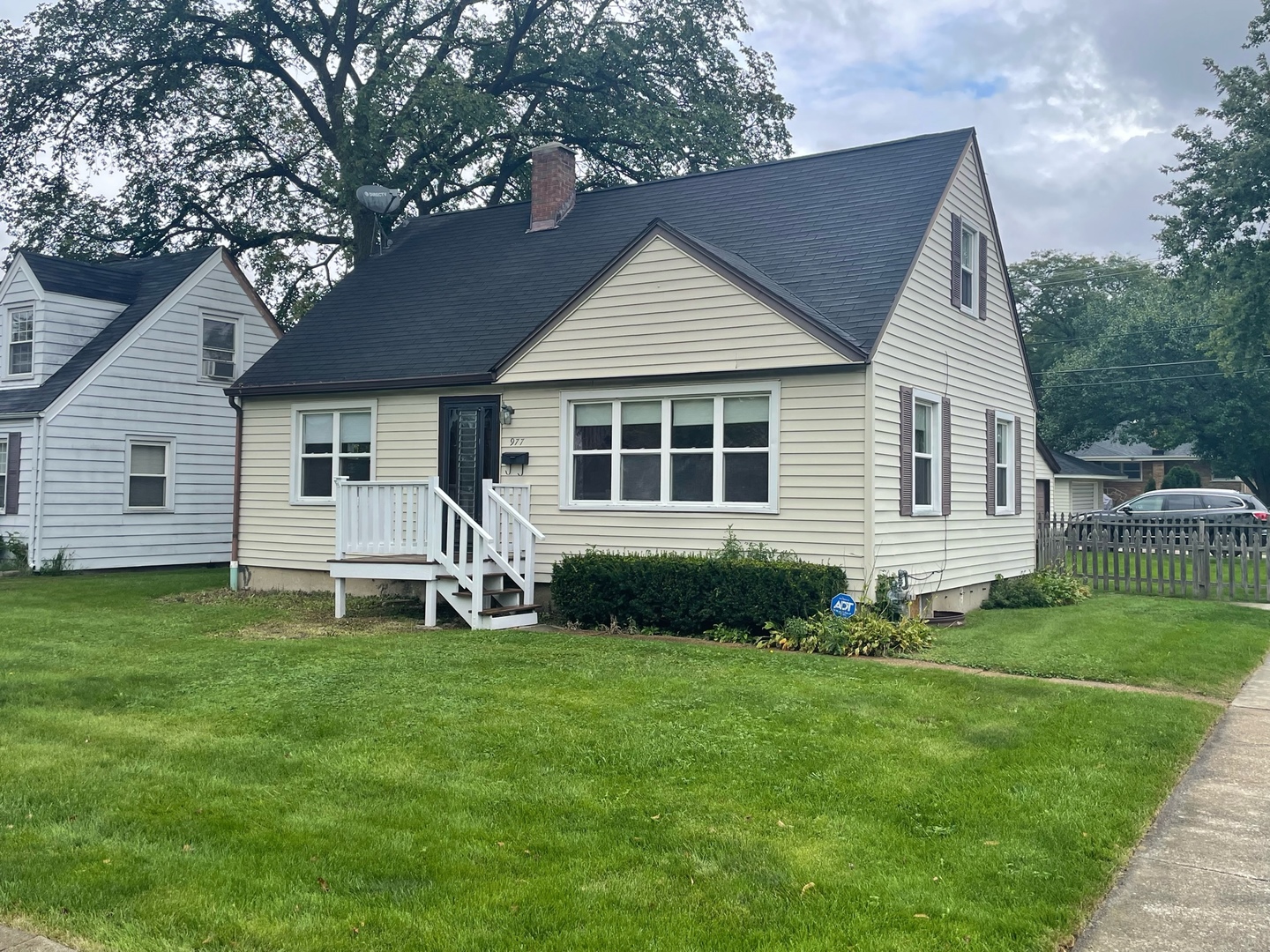 a white house sitting in a big yard with large trees