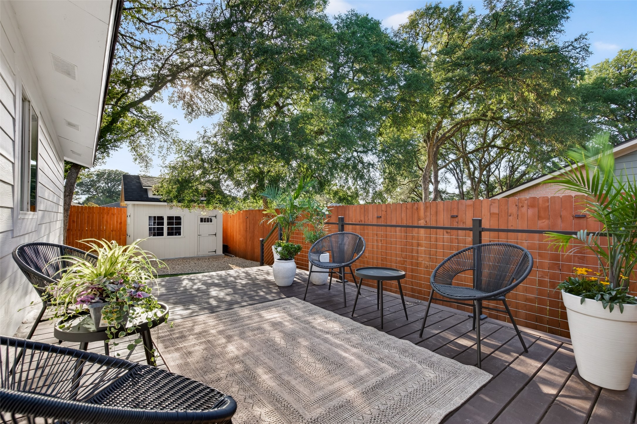 6806 Rearden Road Austin, TX 78745 - Photo 21 of 28 Expansive wood-finish deck with a woven area rug, featuring a privacy fence and mature trees