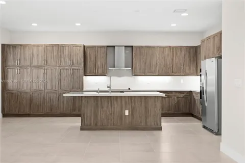 a kitchen with granite countertop wooden cabinets a refrigerator and a sink