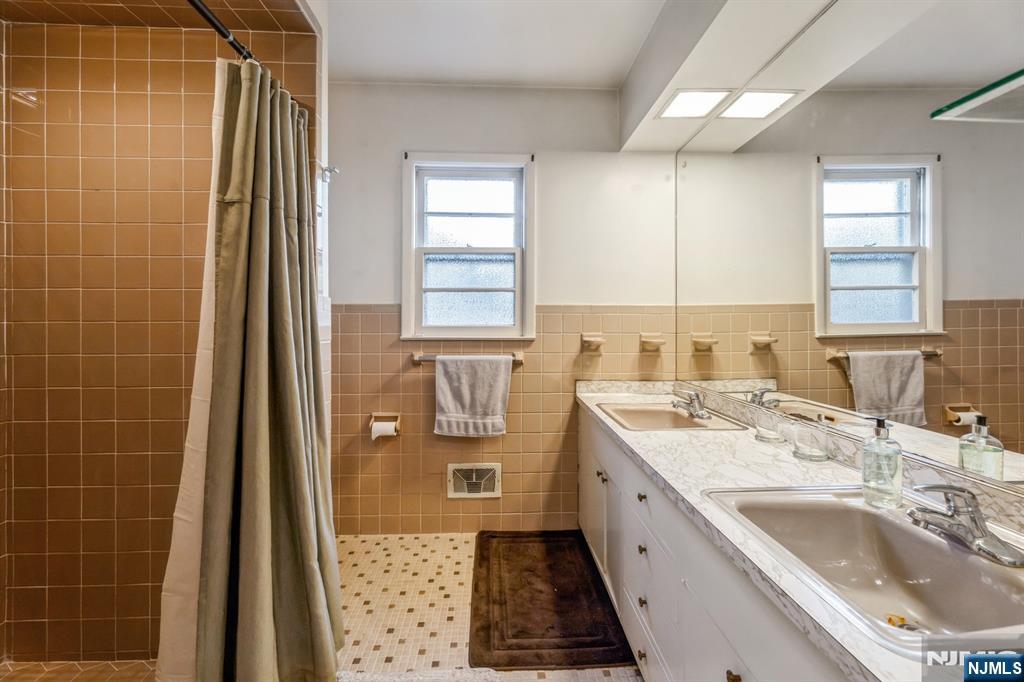 58 Taillon Terrace Closter, NJ 07624 - Photo 15 of 24 a bathroom with a granite countertop sink a mirror and a bathtub
