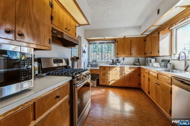 a kitchen with stainless steel appliances granite countertop a sink a stove counter space and cabinets