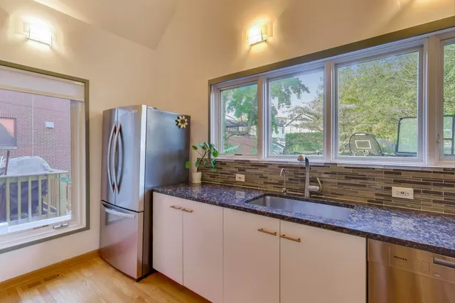 a kitchen with granite countertop a refrigerator a sink and a large window