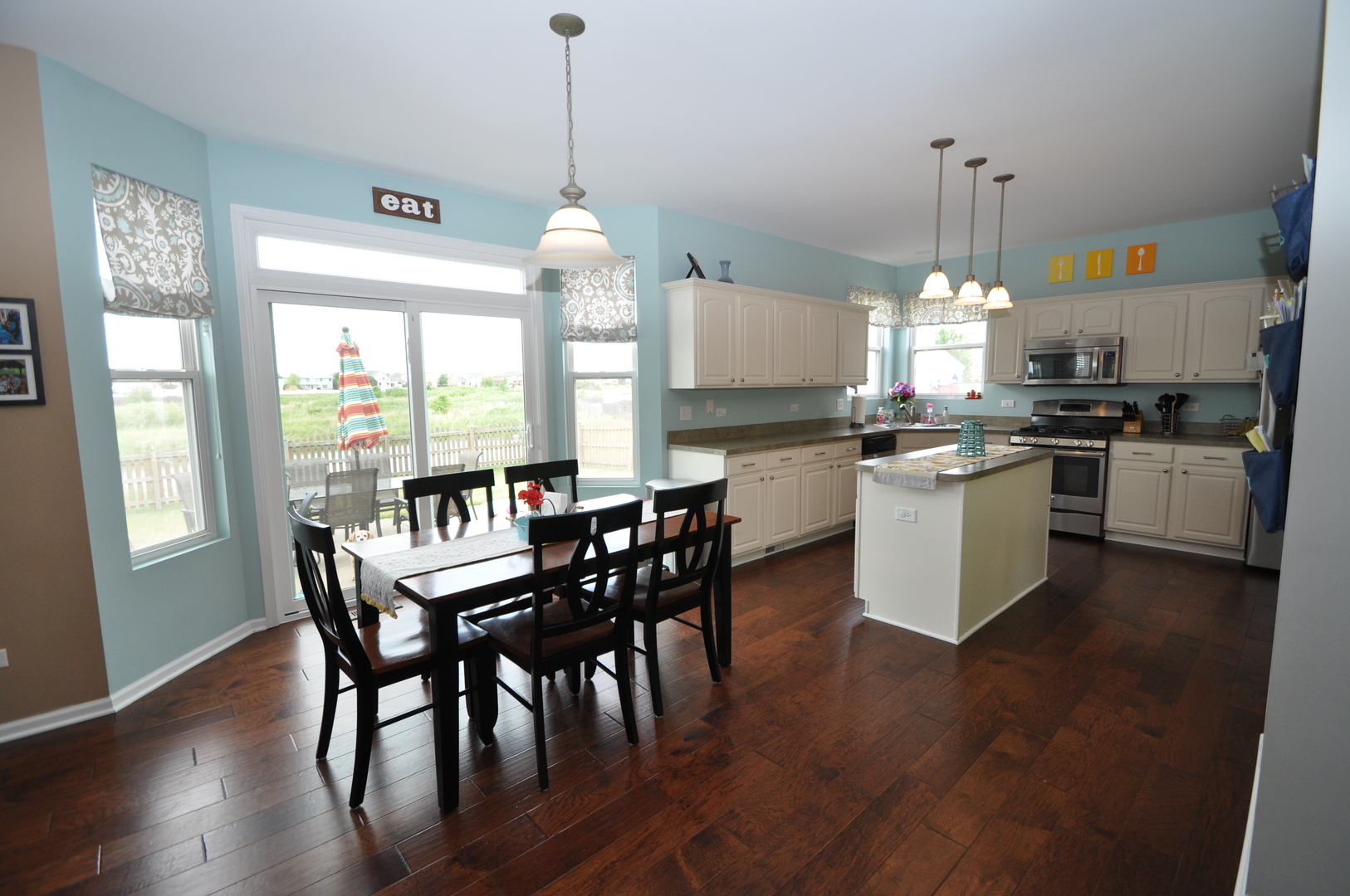 25056 Spring Street Manhattan, IL 60442 - Photo 7 of 24 a kitchen with stainless steel appliances granite countertop a stove a refrigerator a kitchen island a table and chairs