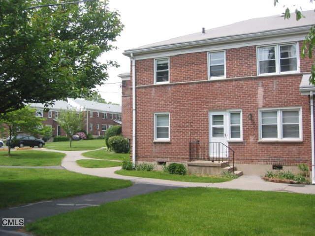238 Glenbrook Road, Unit 32A Stamford, CT 06906 - Photo 1 of 1 a brick house with a yard plants and big trees