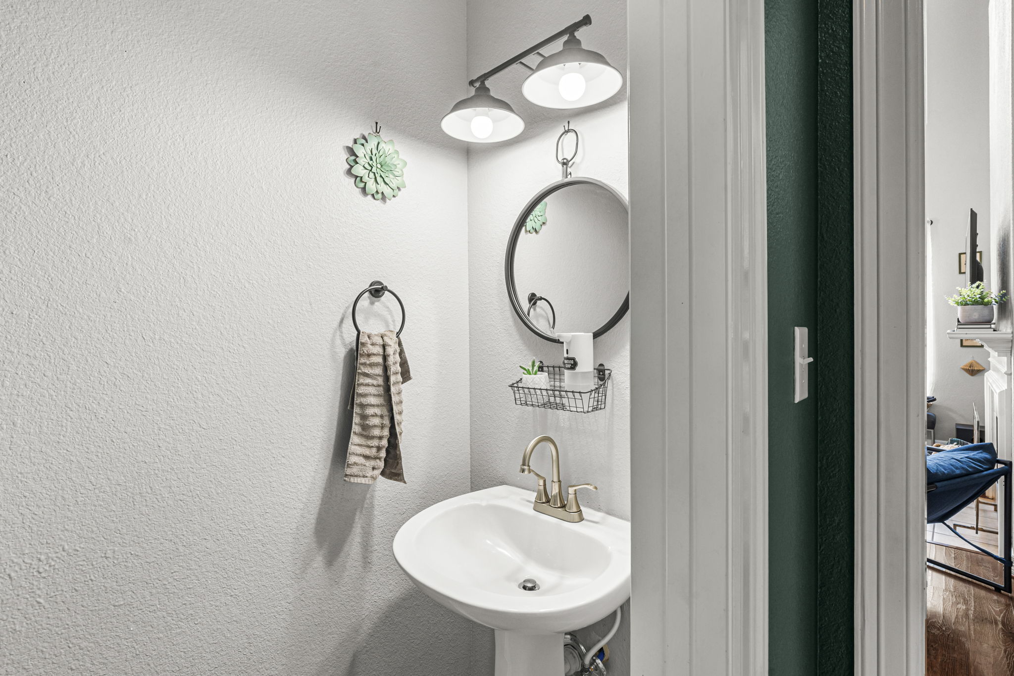 454 Fall Circle Kyle, TX 78640 - Photo 15 of 39 A compact pedestal sink with modern fixtures and a sleek round mirror creates a functional powder room.