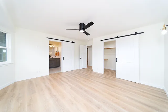 a view of empty room with wooden floor and ceiling fan
