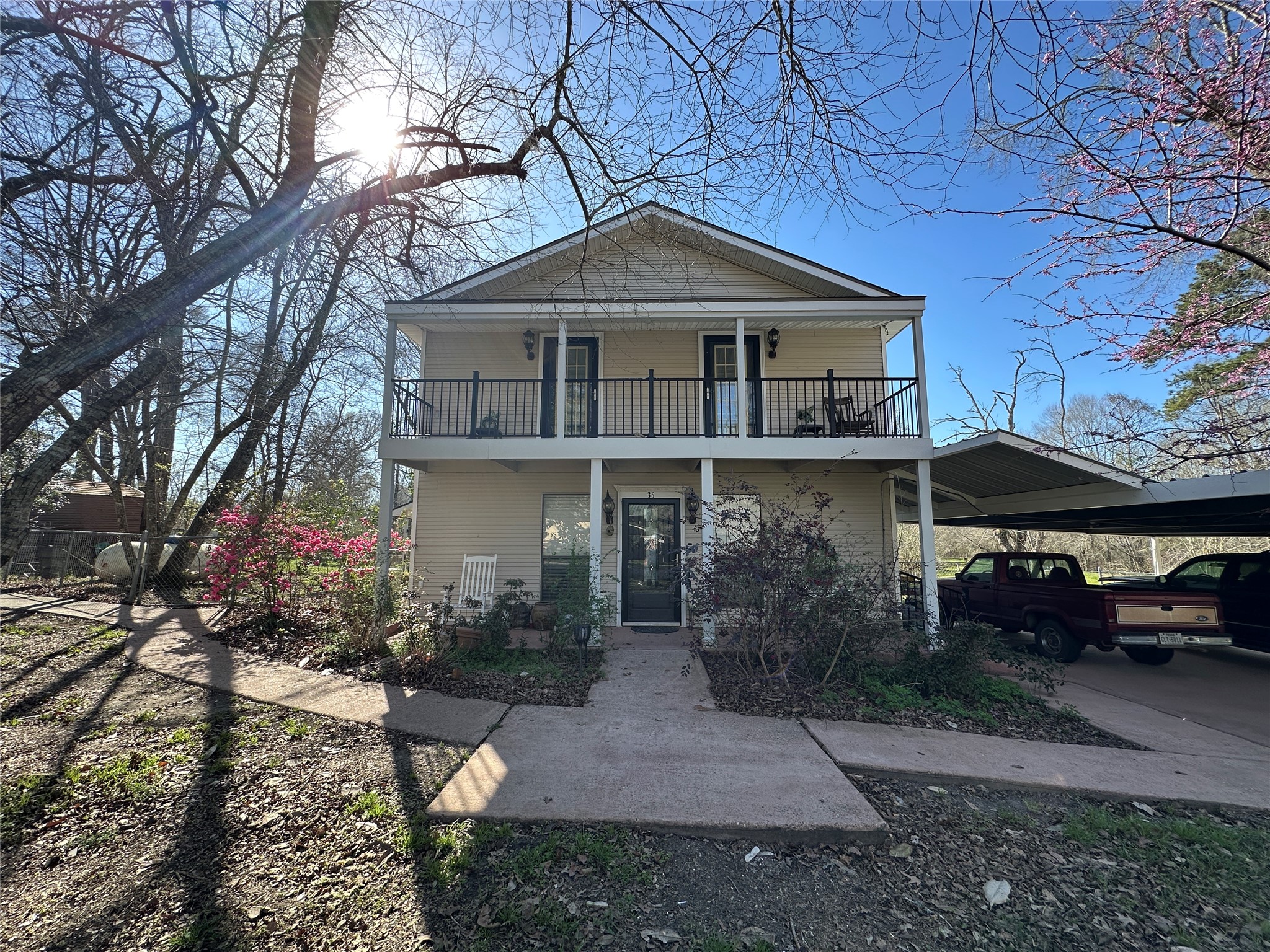 35 Susan Drive Cleveland, TX 77327 - Photo 29 of 33 Charming two-story home with a welcoming front porch and balcony. Surrounded by mature trees and colorful landscaping, it features a spacious carport and a well-maintained exterior. Perfect for enjoying outdoor living.