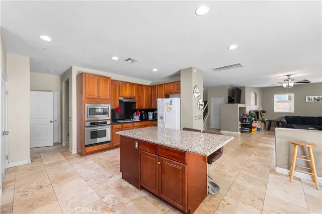 a large kitchen with stainless steel appliances granite countertop a large counter top a sink and a refrigerator