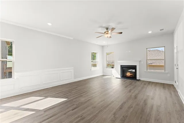 an empty room with wooden floor fireplace and windows