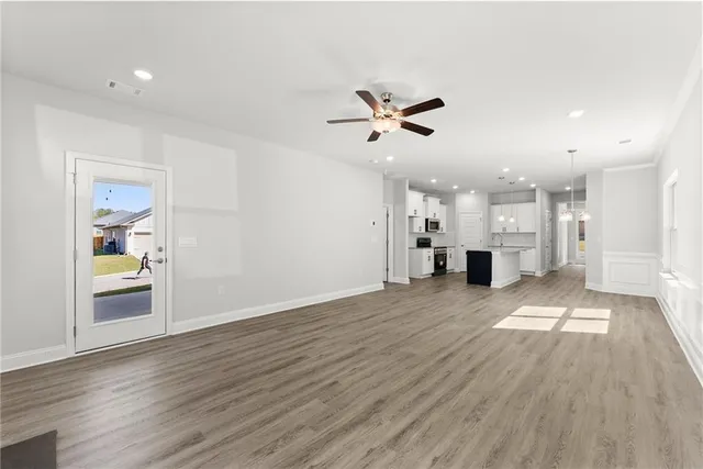 a view of empty room with wooden floor and a kitchen