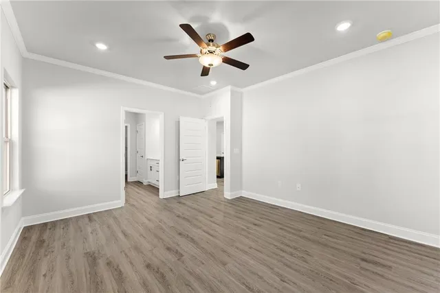 an empty room with wooden floor a ceiling fan and a window