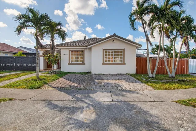 a view of a white house with a yard and palm trees