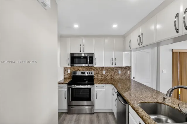 a kitchen with stainless steel appliances granite countertop a sink a stove a refrigerator a microwave and cabinets