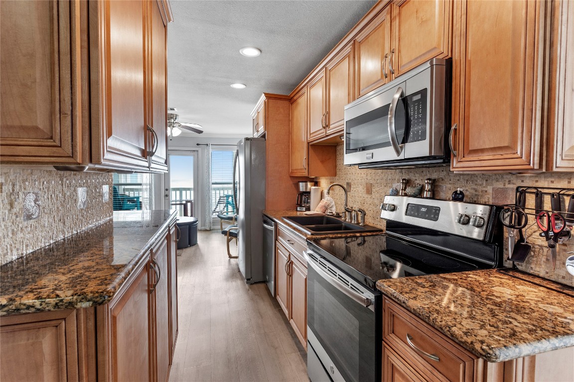 10811 Termini-San Luis Pass Road, Unit 1307 Galveston, TX 77554 - Photo 10 of 28 a kitchen with stainless steel appliances granite countertop a stove a sink and a microwave